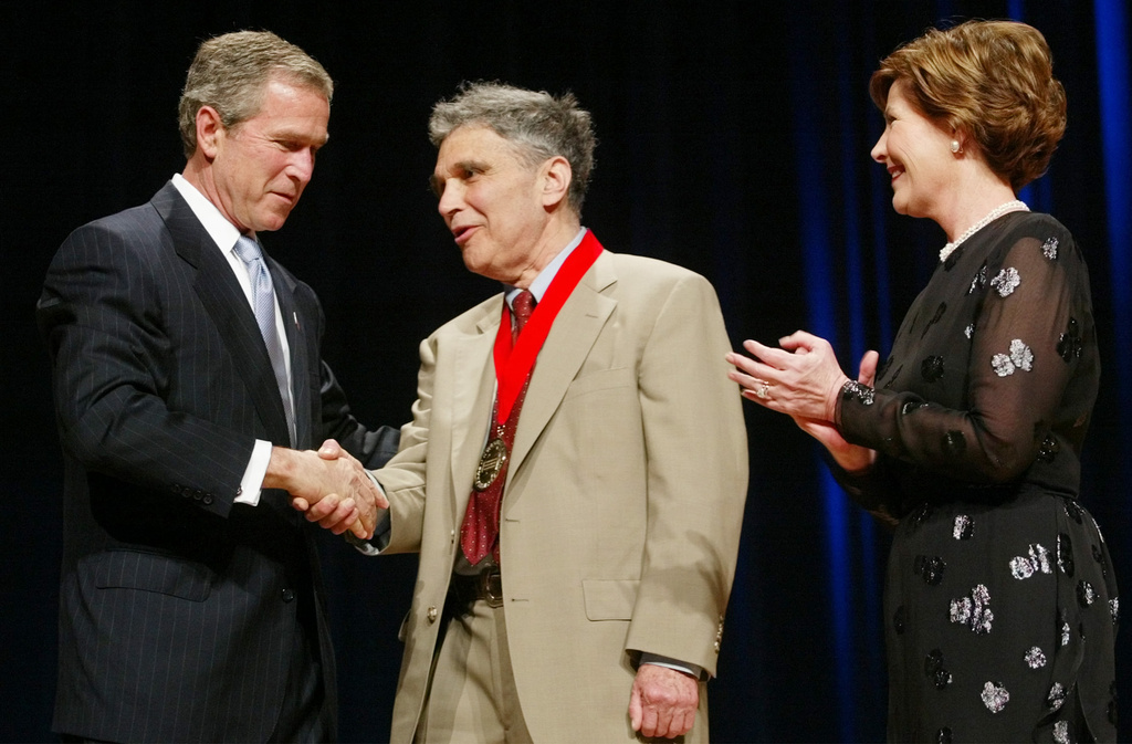 FILE - President Bush, left, shakes hands with Robert Coles, center, a child psychologist, researcher and professor of psychiatry from Cambridge, Mass., as first lady Laura Bush looks on during the National Endowment for the Arts Awards ceremony at Constitution Hall, April 22, 2002, in Washington. (AP Photo/Pablo Martinez Monsivais, File)