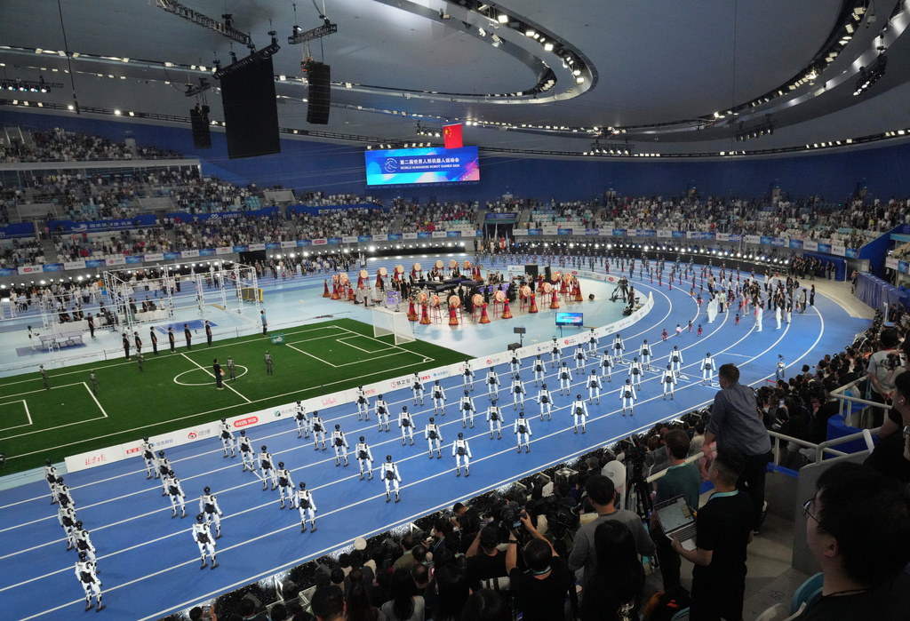 Spectator looking robots perform during the opening ceremony of the World Humanoid Robot Games in Beijing, Saturday, Aug. 22, 2026. (AP Photo/Achmad Ibrahim)
