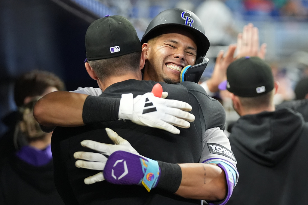 Colorado Rockies' Ezequiel Tovar is embraced in the dugout after hitting a two run home run during the fourth inning of a baseball game against the Miami Marlins, Saturday, March 28, 2026, in Miami. (AP Photo/Lynne Sladky)