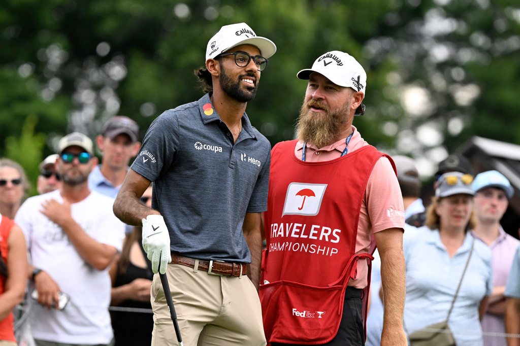 Akshay Bhatia smiles as his caddie Joe Greiner talks to him at the first hole during the third round of the Travelers Championship golf tournament at TPC River Highlands, Saturday, June 27, 2026, in Cromwell, Conn. (AP Photo/Jessica Hill)