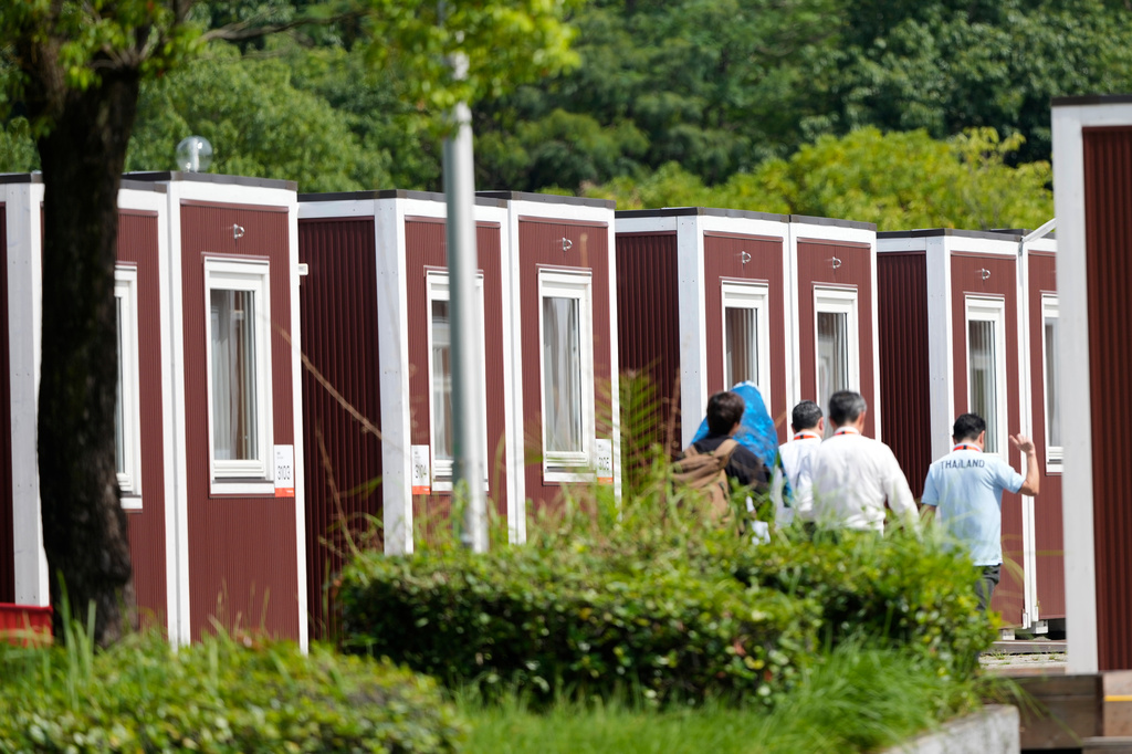 Officials walk past athletes accommodation huts at the Athletes Village ahead of the Asian Games Nagoya, Japan, Friday, Sept. 18, 2026. (AP Photo/Dita Alangkara)