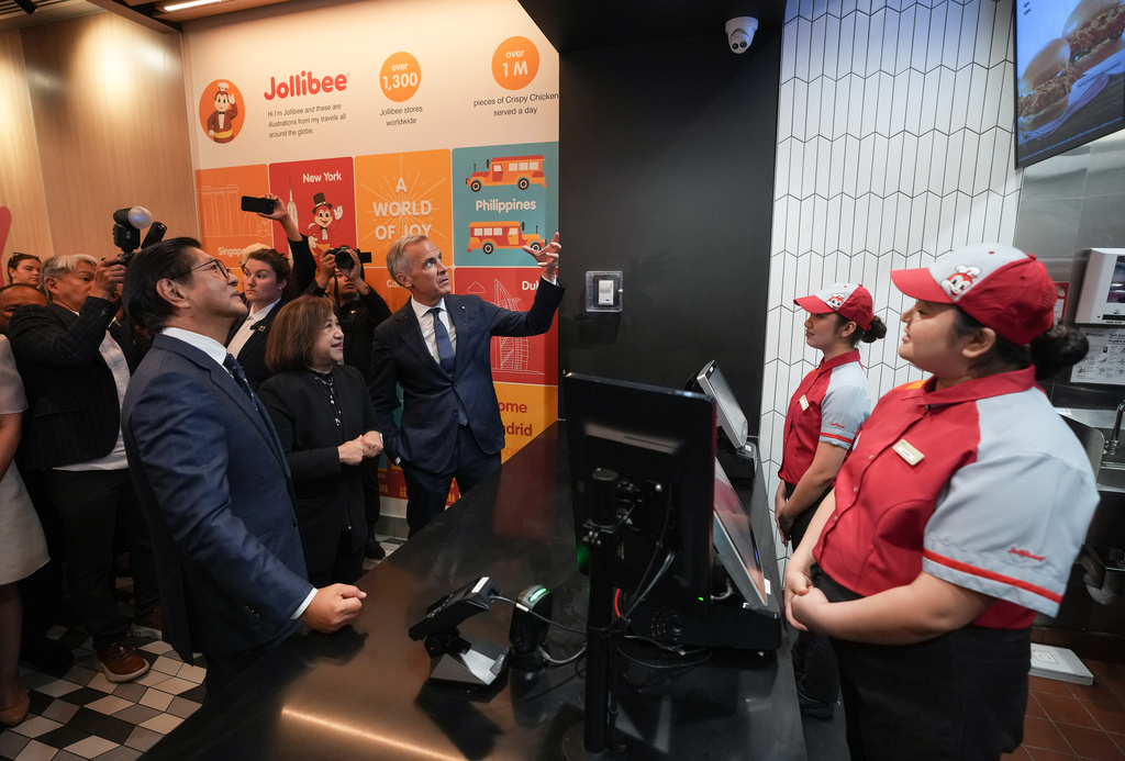 Canada's Prime Minister Mark Carney, back, Philippines President Ferdinand Marcos Jr., left, and Jollibee Group North America president Beth Dela Cruz place an order during a visit to a Jollibee fast food restaurant, in Vancouver, Thursday, July 2, 2026. (Darryl Dyck/The Canadian Press via AP)