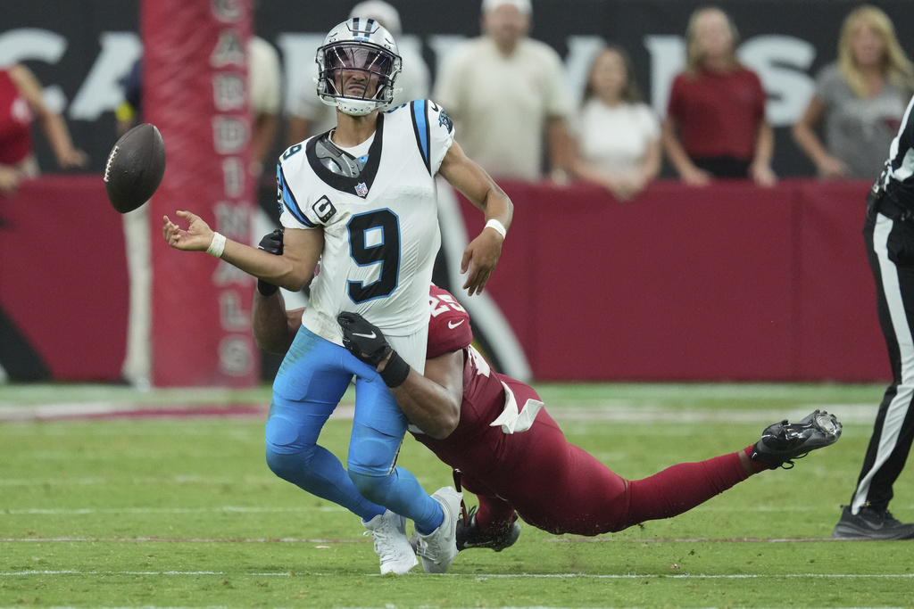 Carolina Panthers quarterback Bryce Young (9) loses the ball as he is hit by Arizona Cardinals defensive tackle Calais Campbell during the second half of an NFL football game, Sunday, Sept. 14, 2025, in Glendale, Ariz. (AP Photo/Ross D. Franklin)