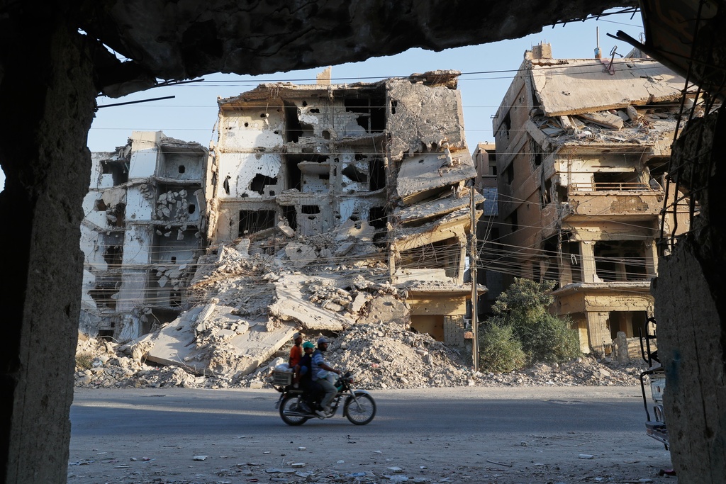 Residents ride a motorcycle past war-damaged buildings in the Damascus suburb of Daraya, Syria, Saturday, Oct. 4, 2025, ahead of a parliamentary election set to take place Sunday. (AP Photo/Omar Sanadiki)