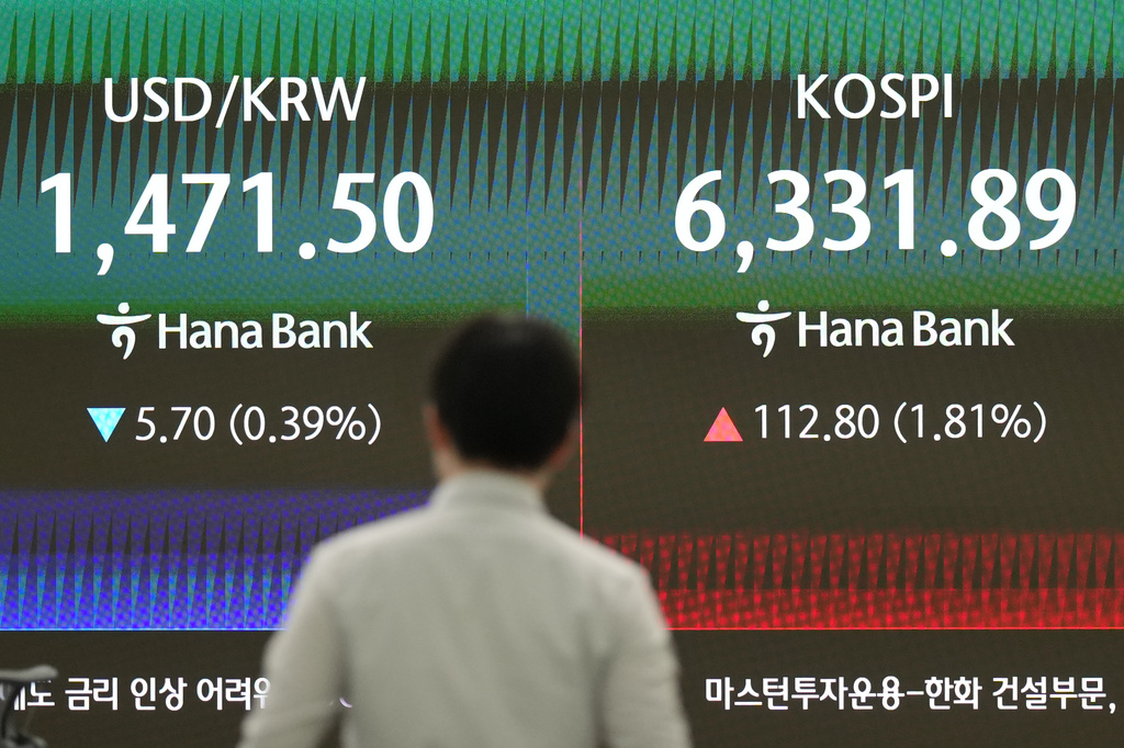 A dealer walks past the screens showing the Korea Composite Stock Price Index (KOSPI) and the foreign exchange rate between U.S. dollar and South Korean won at a dealing room of Hana Bank in Seoul, South Korea, Tuesday, April 21, 2026. (AP Photo/Lee Jin-man)