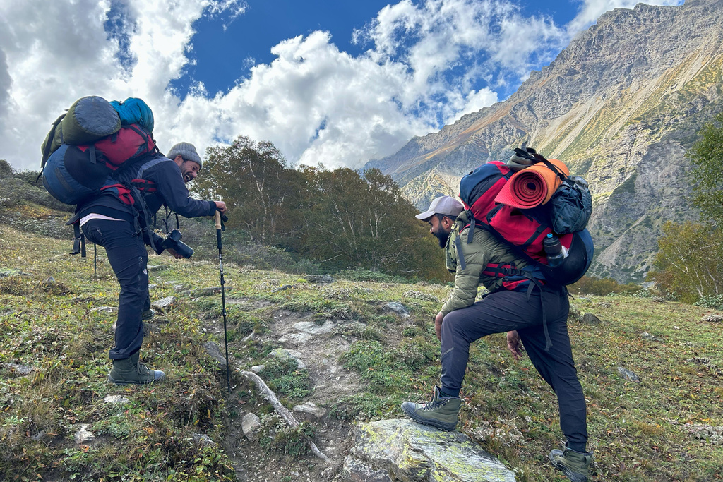 Trekking guides Pawan Koranga, left, and Raju Goswmi stop to catch their breath as they accompany a client to the Nanda Devi base camp, in the northern Indian Himalayan state of Uttarakhand, on Sept. 30, 2025. (AP Photo/Satish Sharma)
