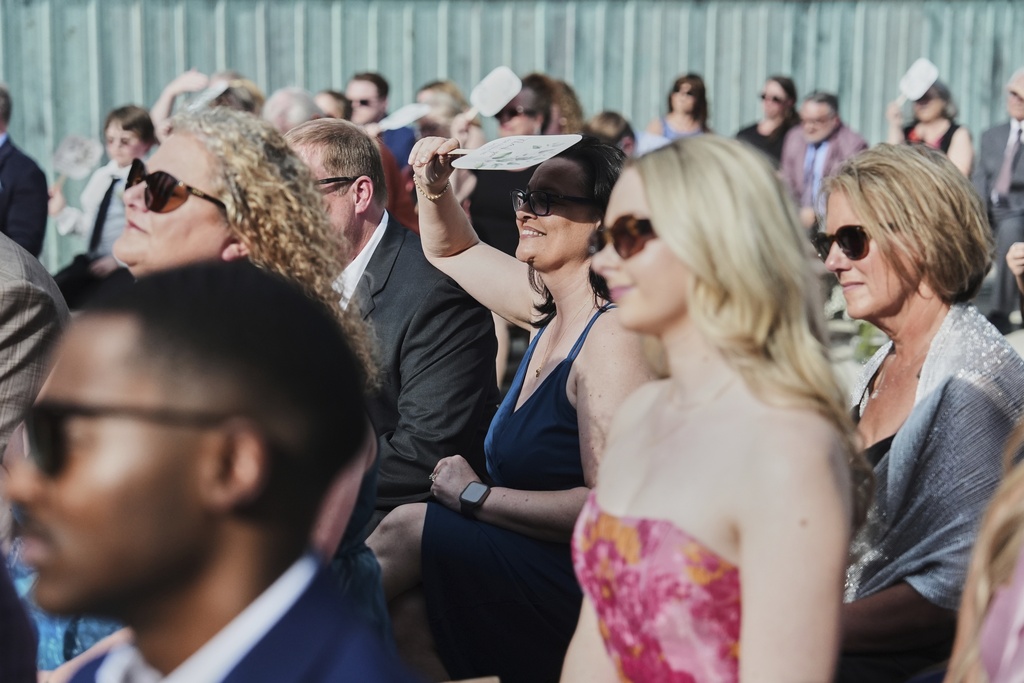 A guest uses a fan to shade from the sun during a wedding ceremony Saturday, Aug. 23, 2025, in Newtown, Ohio. (AP Photo/Joshua A. Bickel)