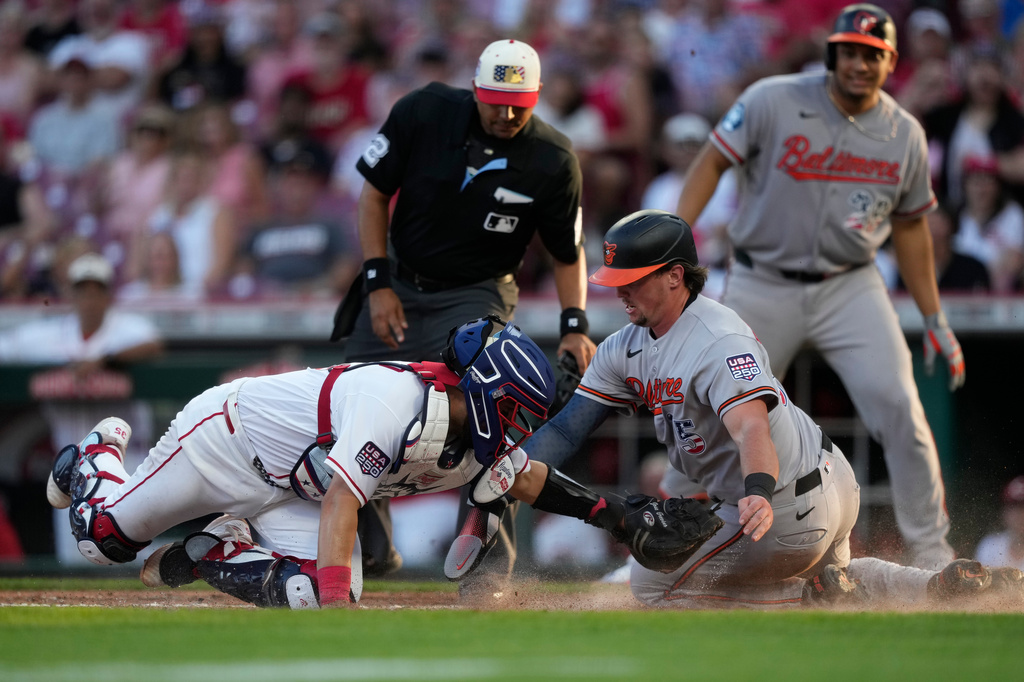 Baltimore Orioles Adley Rutschman, right, is tagged out by Cincinnati Reds catcher Jose Trevino, left, as during the third inning of a baseball game in Cincinnati, Saturday, July 4, 2026. (AP Photo/Carolyn Kaster)