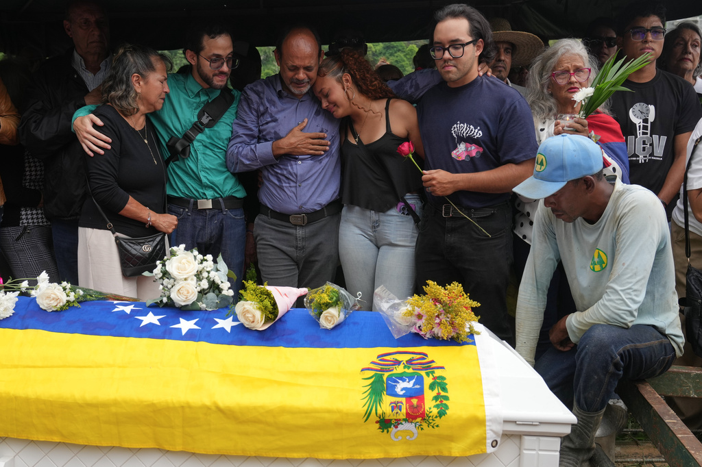 Relatives and friends of Carmen Navas, the mother of Victor Hugo Quero who Venezuelan authorities said died in custody following his arrest about a year earlier, stand by her casket during her burial in Caracas, Venezuela, Tuesday, May 19, 2026. (AP Photo/Ariana Cubillos)