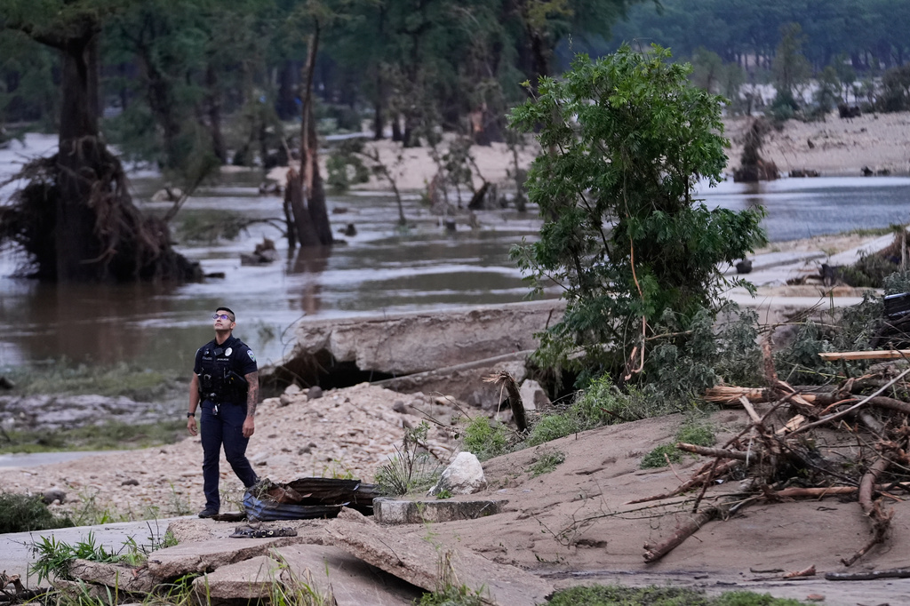 A police officer walks along the Guadalupe River after a series of storms on Friday, July 17, 2026, in Kerrville, Texas. (AP Photo/Gerald Herbert)