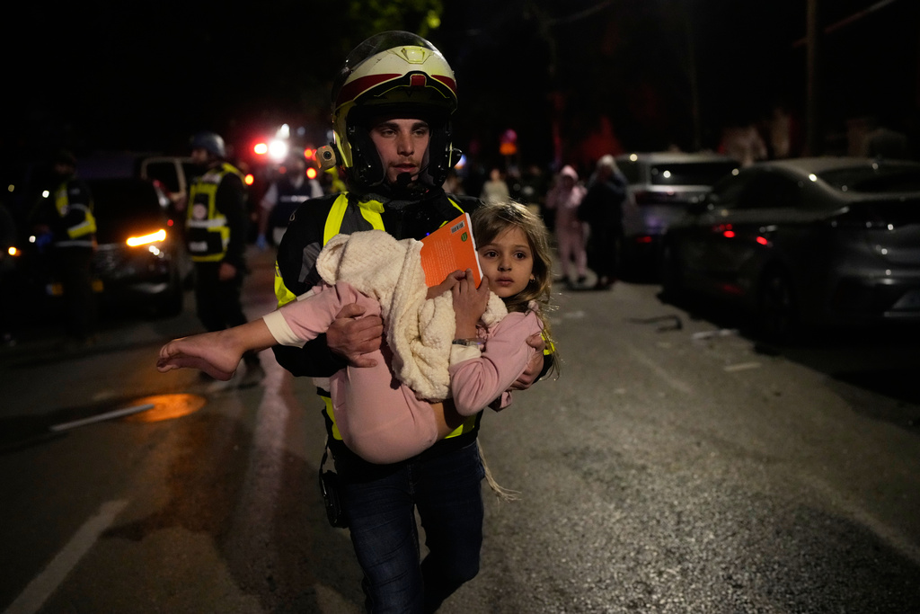 An Israeli rescue personal carries a child after missiles attack from Iran hit in Tel Aviv, Israel, Saturday, Feb. 28, 2026. (AP Photo/Ohad Zwigenberg)