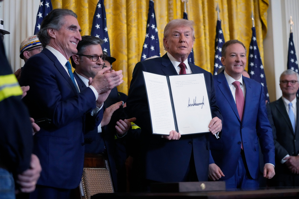 President Donald Trump holds up an executive order he just signed during an event on coal power in the East Room at the White House, Wednesday, Feb. 11, 2026, in Washington. Looking on at right is EPA Administrator Lee Zeldin, House Speaker Mike Johnson, center, and Interior Secretary Doug Burgum at left. (AP Photo/Mark Schiefelbein)