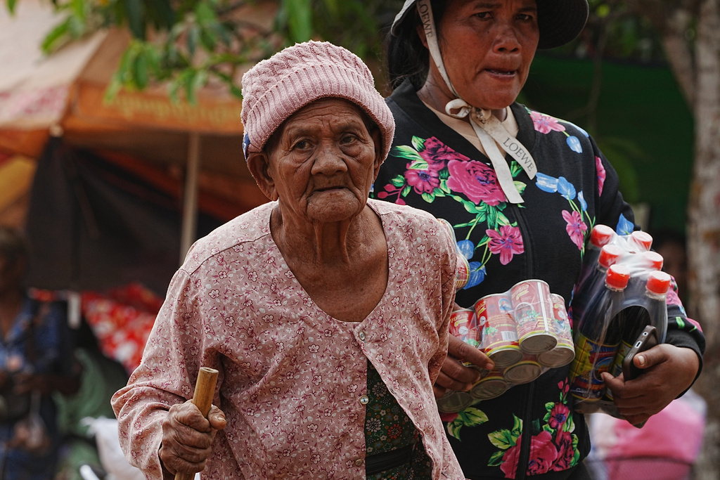 A woman, left, walks as she takes refuge at Batthkoa primary school in Oddar Meanchey province, Cambodia Wednesday, Dec. 10, 2025, after fleeing from home following fighting between Thailand and Cambodia over territorial claims. (AP Photo/Heng Sinith)