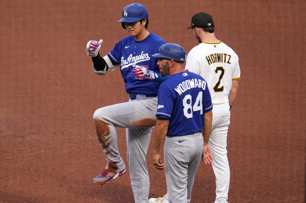 Los Angeles Dodgers' Shohei Ohtani, left, celebrates as he stands on first base after hitting a single off Pittsburgh Pirates pitcher Mitch Keller during the fourth inning of a baseball game in Pittsburgh, Thursday, June 11, 2026. (AP Photo/Gene J. Puskar)