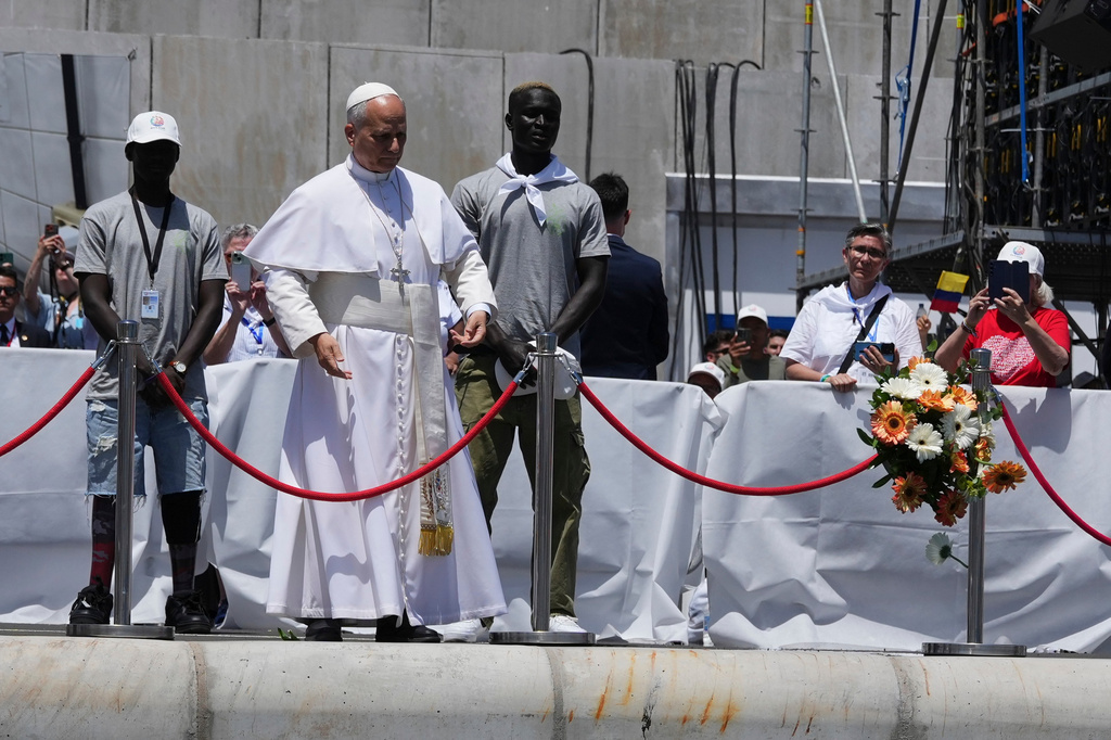 Pope Leo XIV throws a bouquet of flowers into the sea, flanked by migrants, during a meeting with organisations working with migrants in Arguineguin at the Canary Islands, Spain, Thursday, June 11, 2026. (AP Photo/Alessandra Tarantino)