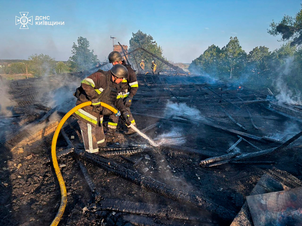 In this photo provided by the Ukrainian Emergency Service, emergency services personnel work to extinguish a fire following a Russian drone attack in Kyiv region, Ukraine, Tuesday, May 12, 2026. (Ukrainian Emergency Service via AP)