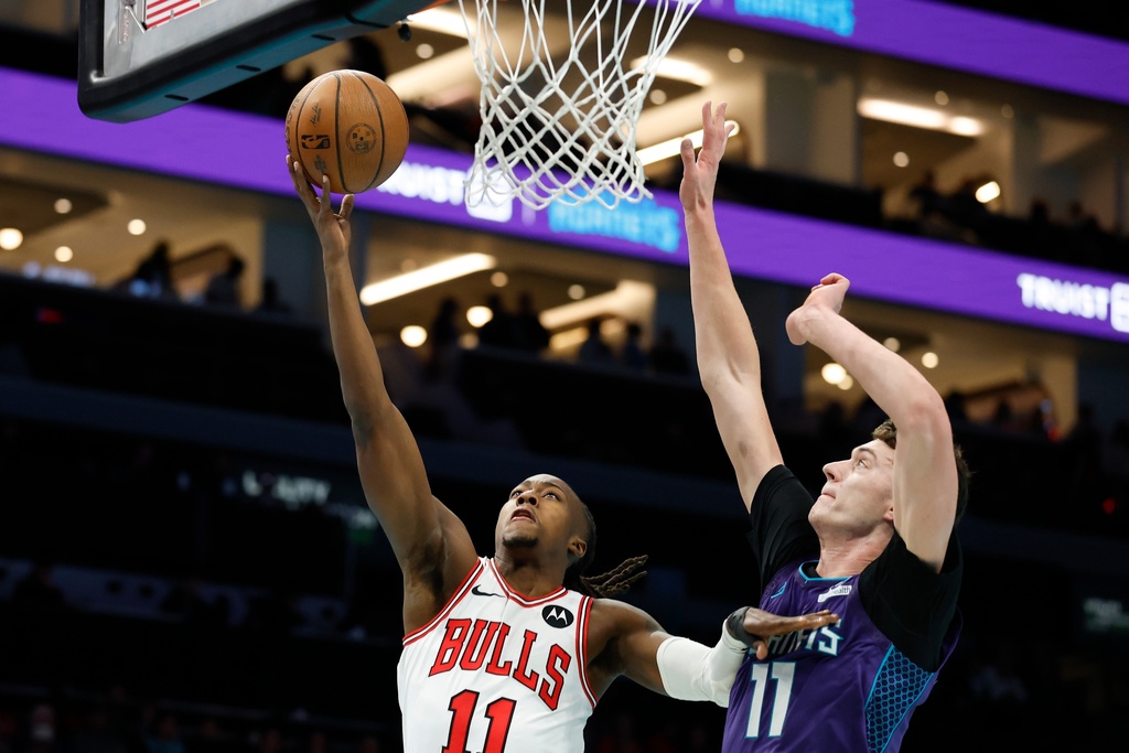 Chicago Bulls guard Ayo Dosunmu, left, shoots against Charlotte Hornets center Ryan Kalkbrenner during the first half of an NBA Cup basketball game in Charlotte, N.C., Friday, Nov. 28, 2025. (AP Photo/Nell Redmond)