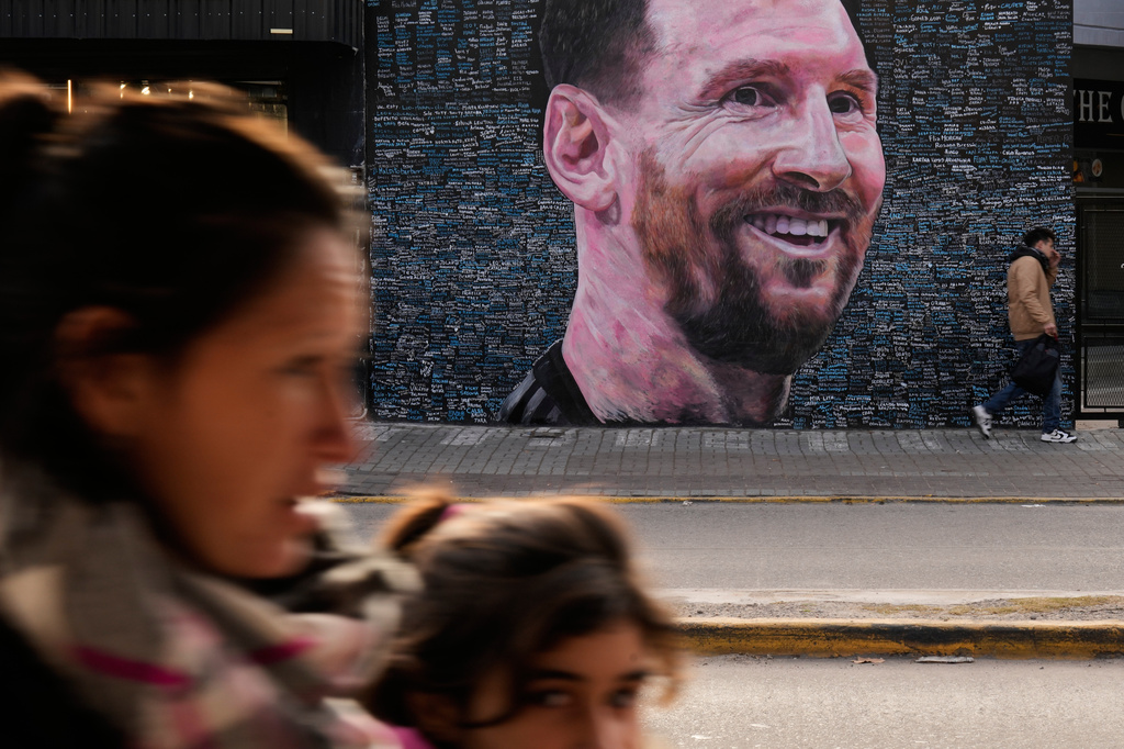 People walk past a mural of Lionel Messi by artist Leonel Garcia, which includes the names of local residents inscribed by them as a tribute to the soccer star, in Berazategui, on the outskirts of Buenos Aires, Argentina, Monday, June 22, 2026. (AP Photo/Gustavo Garello)