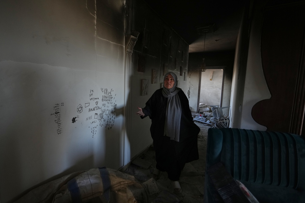 Ihsan Yaghi gestures inside her fire-damaged home, showing what she says, is graffiti left by Israeli forces, following a military operation, in Zawtar al-Gharbieh, Lebanon, Tuesday, July 28, 2026. (AP Photo/Hassan Ammar)