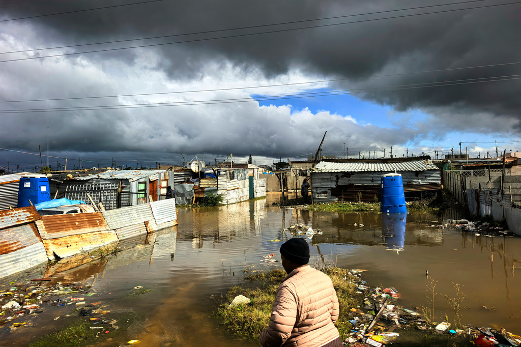 A woman walks on a waterlogged pathway of the informal settlement in Khayelitsha, on the outkirks of Cape Town, South Africa, Tuesday, May 12, 2026. (AP Photo/Bheki Radebe)