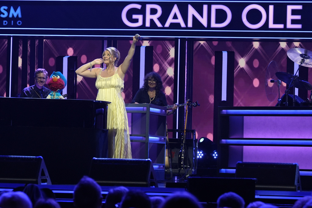 Sesame Street's Elmo, left, performs with Lauren Alaina at the Grand Ole Opry, Thursday, Aug. 14, 2025, in Nashville, Tenn. (AP Photo/George Walker IV)