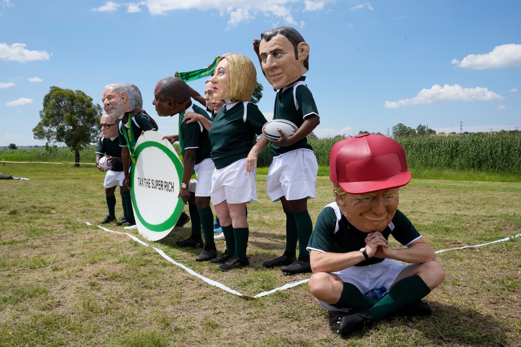 Demonstrators wearing big heads of world leaders protest in Soweto during the opening session of the G20 leaders' summit in Johannesburg, South Africa, Saturday, Nov. 22, 2025. (AP Photo/Themba Hadebe)