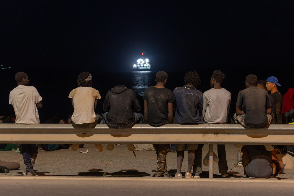 Migrants who crossed into Spain from Morocco gather on a beach in the Spanish enclave of Ceuta, Sunday, Aug. 2, 2026. (AP Photo/Antonio Sempere)