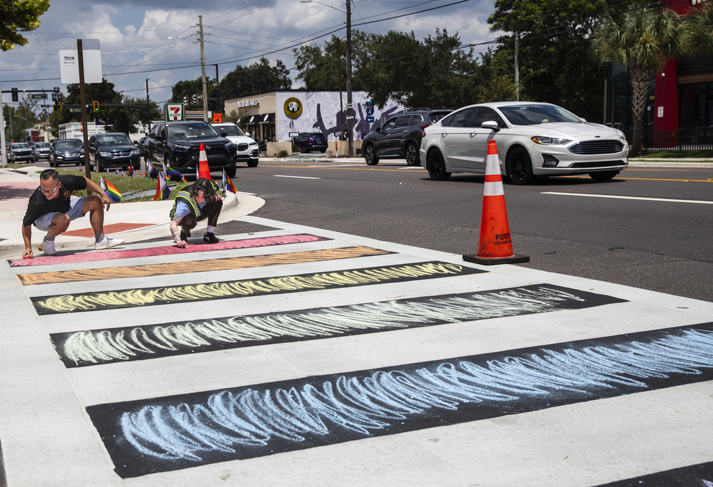 Sen. Carlos Guillermo Smith helps Dallas Perdew color the sidewalk with chalk she brought to bring color back to the intersection in Orlando, Fla., Thursday, Aug. 21, 2025. (Willie J. Allen Jr./Orlando Sentinel)