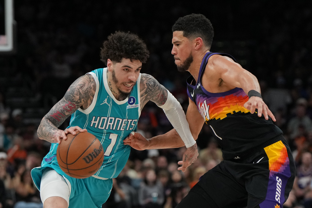 Charlotte Hornets guard LaMelo Ball (1) drives on Phoenix Suns guard Devin Booker during the second half of an NBA basketball game, Sunday, March 8, 2026, in Phoenix. (AP Photo/Rick Scuteri)