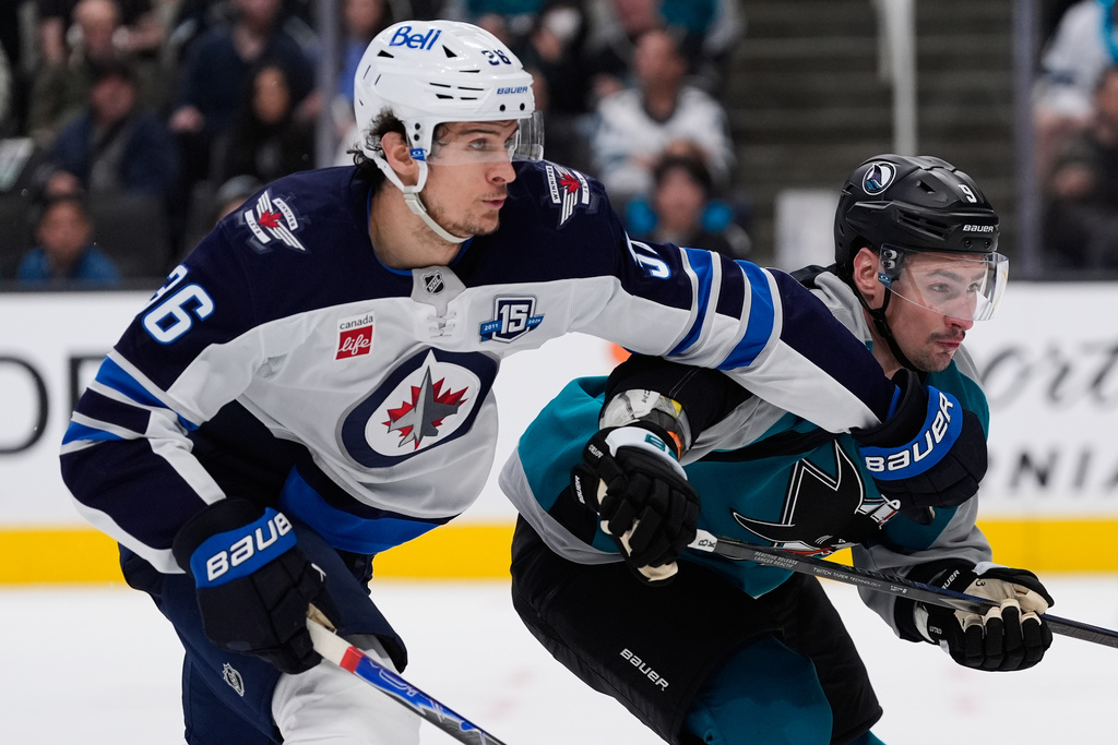 Winnipeg Jets center Morgan Barron (36) and San Jose Sharks defenseman Dmitry Orlov (9) chase after the puck during the second period of an NHL hockey game, Sunday, March 1, 2026, in San Jose, Calif. (AP Photo/Godofredo A. Vásquez)
