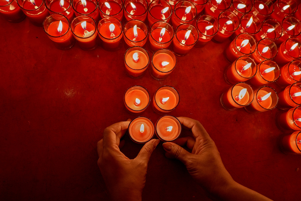An ethnic Chinese Thai lays down candles after praying at the Leng Nuei Yee Chinese temple ahead of Chinese Lunar New Year in Bangkok, Thailand, Monday, Feb. 16, 2026. (AP Photo/Sakchai Lalit)