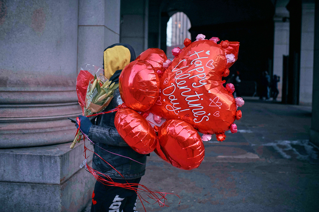 FILE - A man walks holding flowers and balloons on Valentine's Day, Friday, Feb. 14, 2025, in New York. (AP Photo/Andres Kudacki, File)