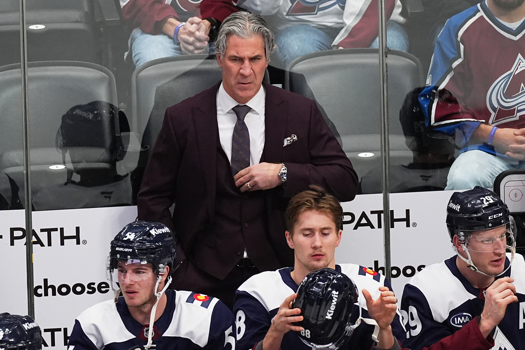 Colorado Avalanche head coach Jared Bednar, top, looks on from the team box in the first period of an NHL hockey game against the Winnipeg Jets, Friday, Dec. 19, 2025, in Denver. (AP Photo/David Zalubowski)