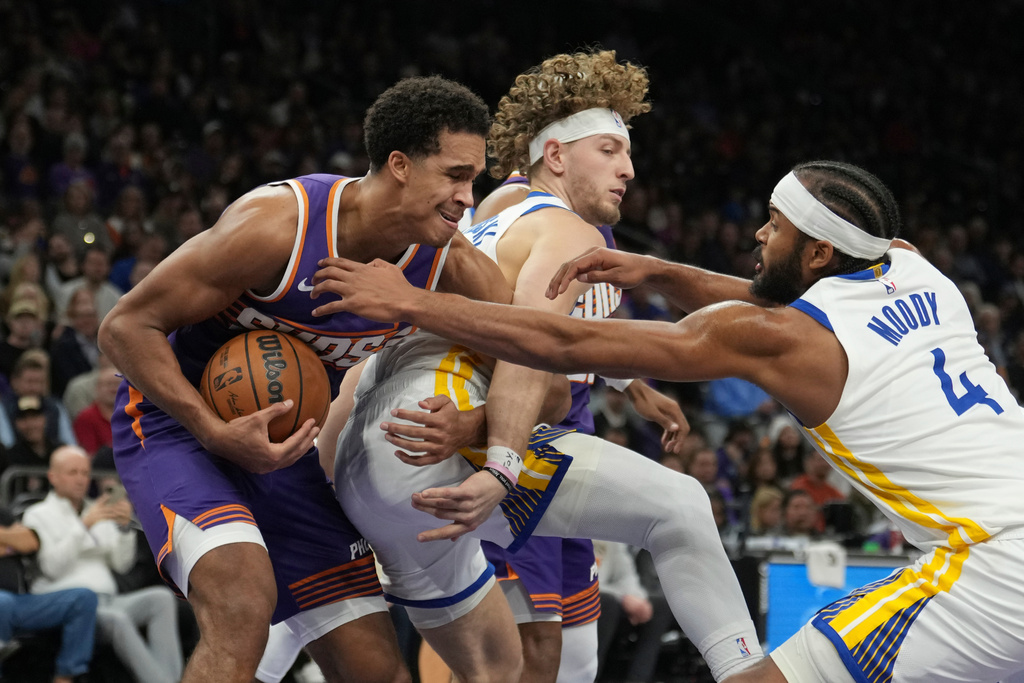 Phoenix Suns forward Oso Ighodaro, left, grabs a rebound against Golden State Warriors guard Brandin Podziemski, center, and Warriors guard Moses Moody (4) during the first half of an NBA basketball game Thursday, Dec. 18, 2025, in Phoenix. (AP Photo/Ross D. Franklin)