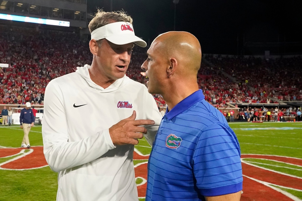 Mississippi head coach Lane Kiffin, left, and Florida interim head coach Billy Gonzales confer prior to the start of an NCAA college football game, Saturday, Nov. 15, 2025, in Oxford, Miss. (AP Photo/Rogelio V. Solis)