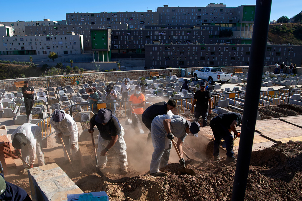 Funeral workers bury migrants who died while trying to cross from Morocco into the Spanish exclave of Ceuta, Friday, Aug. 21, 2026. (AP Photo/Antonio Sempere)
