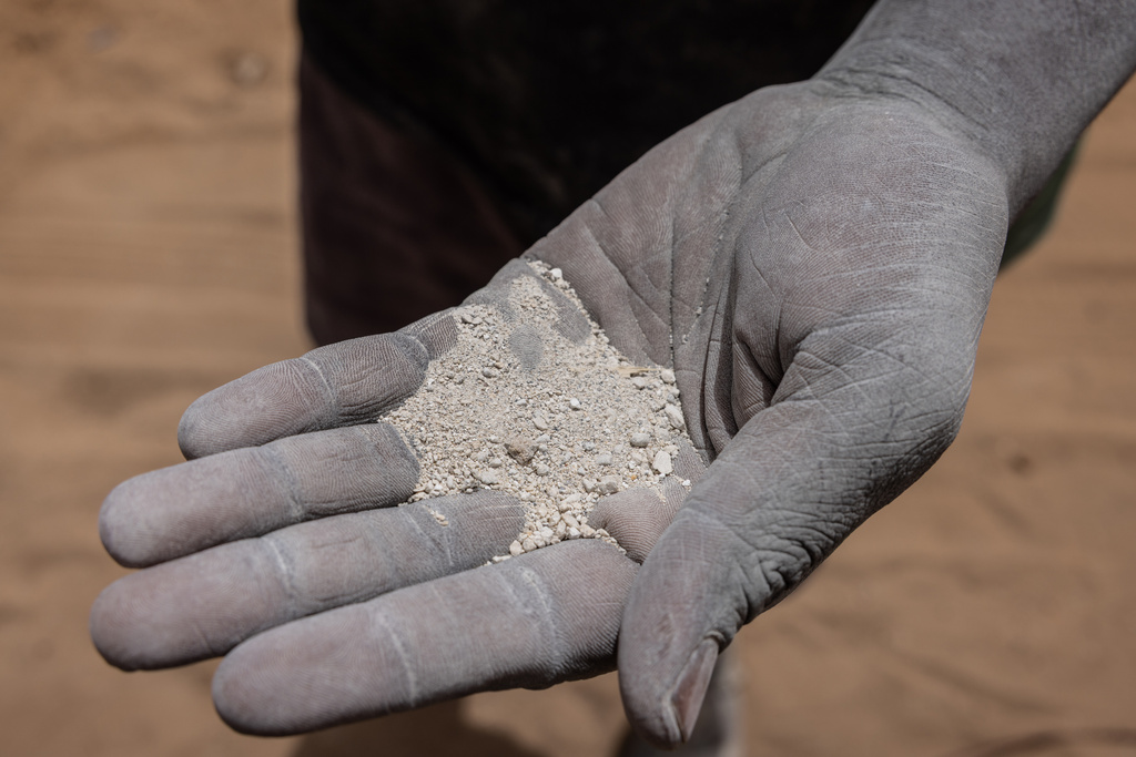 A worker shows the chemical fertilizer that is used across the country in Thies, Senegal, Tuesday, May 12, 2026. (AP Photo/Caitlin Kelly)