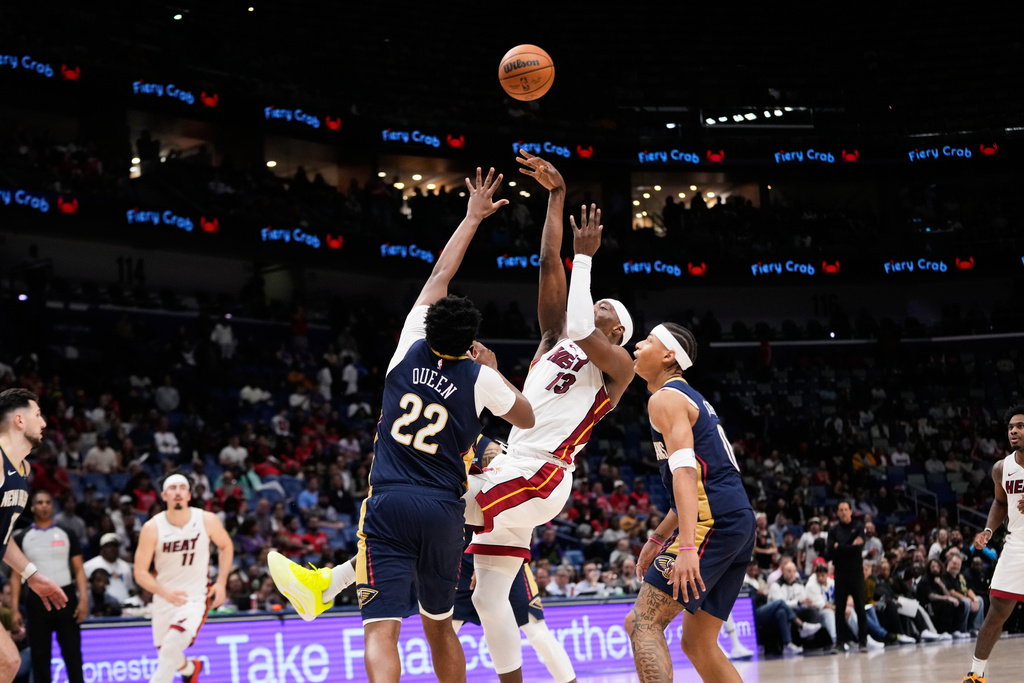 Miami Heat center Bam Adebayo (13) shoots against New Orleans Pelicans center Derik Queen (22) and guard Jeremiah Fears (0) in the second half of an NBA basketball game, Wednesday, Feb. 11, 2026, in New Orleans. (AP Photo/Gerald Herbert)