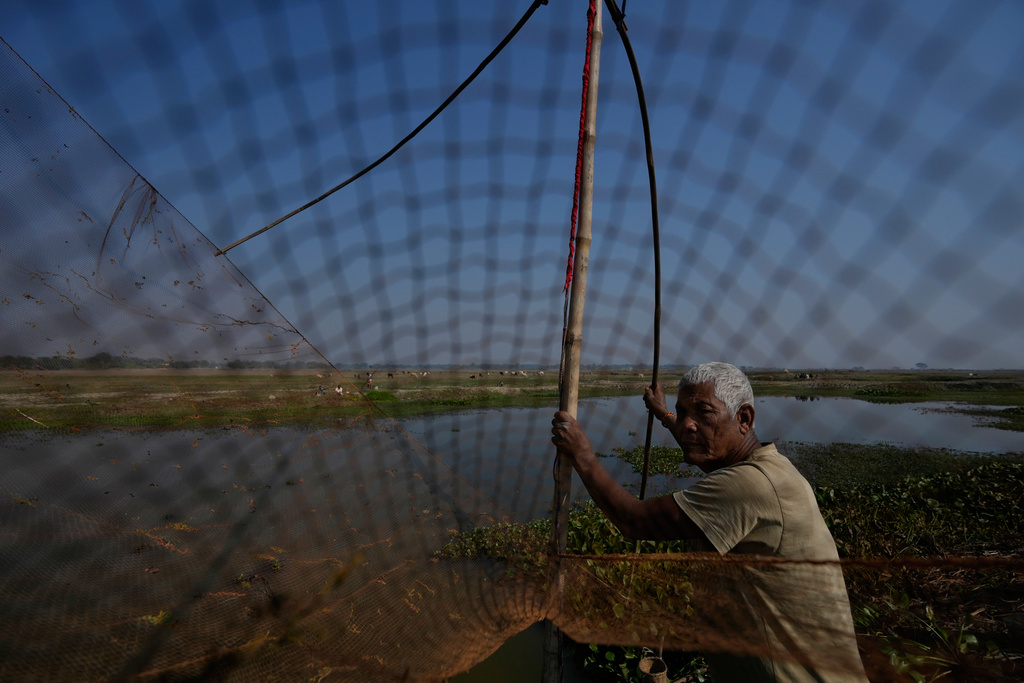 A villager with his fishing net waits to participate in a community fishing as part of Bhogali Bihu celebrations which mark the end of the harvest season at Jalikhora village east of Guwahati, India, Tuesday, Jan. 13, 2026. (AP Photo/Anupam Nath)
