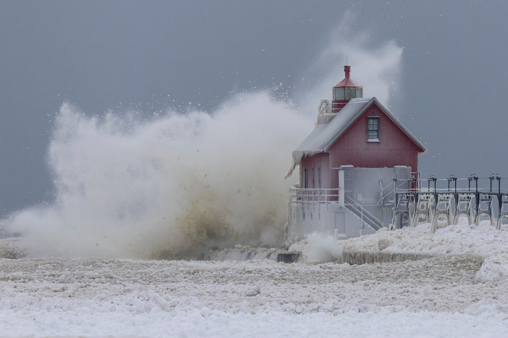 A large wave from Lake Michigan sends ice balls into the air as it crashes into the South Pierhead Outer Light at Grand Haven State Park in Grand Haven, Mich., Monday, Jan. 19, 2026. (Joel Bissell/Kalamazoo Gazette via AP)