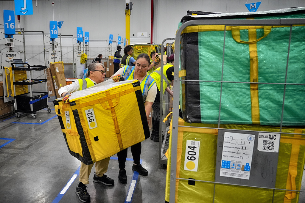 Amazon employees load packages on carts before being put on to trucks for distribution customers for Amazon's annual Prime Day event at an Amazon's DAX7 delivery station on July 16, 2024, in South Gate, Calif. (AP Photo/Richard Vogel)