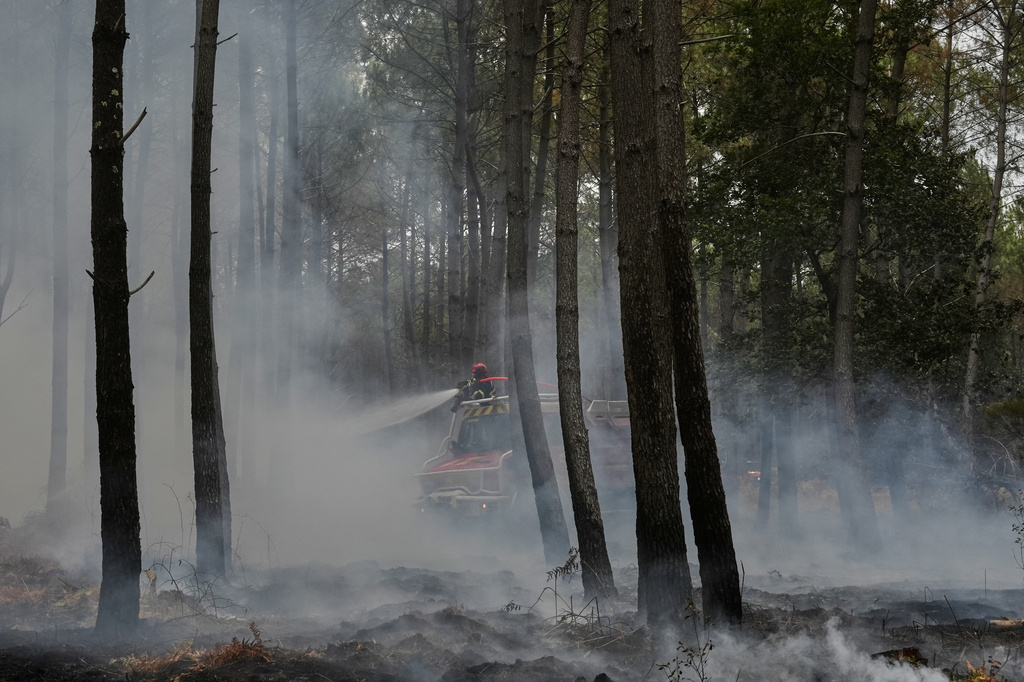 Firefighters work to extinguish a fire, near Blagon, southwestern France, Friday, July 31, 2026. (AP Photo/Baz Ratner)