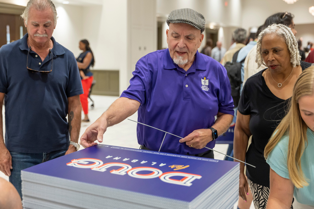 FILE - Michael Davis, of Bellwood, Ala., picks up a sign supporting Doug Jones for governor after a town hall hosted by Troy University College Democrats and the Pike County Democrats, Aug. 18, 2026, in Troy, Ala. (AP Photo/Vasha Hunt, File)