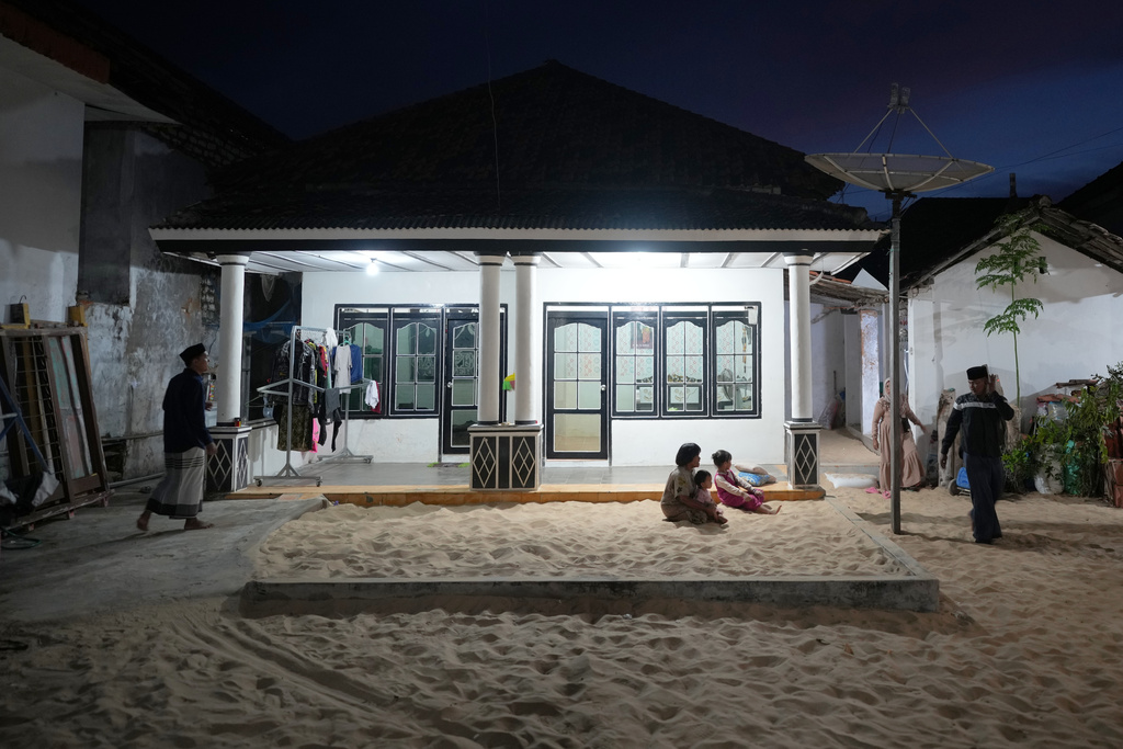 Children play in a sandpit outside a house in Legung Timur village in Sumenep on Madura Island, Indonesia, Tuesday, Sept. 9, 2025. (AP Photo/Dita Alangkara)