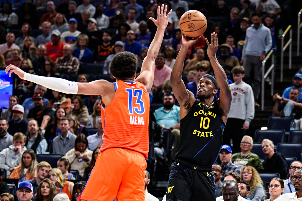 Golden State Warriors forward Jimmy Butler III (10) shoots against Oklahoma City Thunder forward Ousmane Dieng (13) during the first half of an NBA basketball game, Tuesday, Nov. 11, 2025, in Oklahoma City. (AP Photo/Gerald Leong)