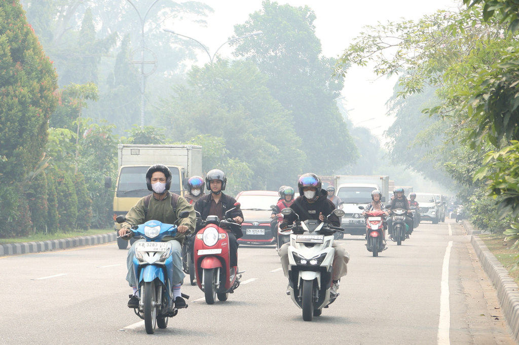 Motorists ride on a road as haze from wildfires blankets the city of Pontianak, West Kalimantan, Indonesia, Friday, Aug. 21, 2026. (AP Photo/Stefanus Taman)