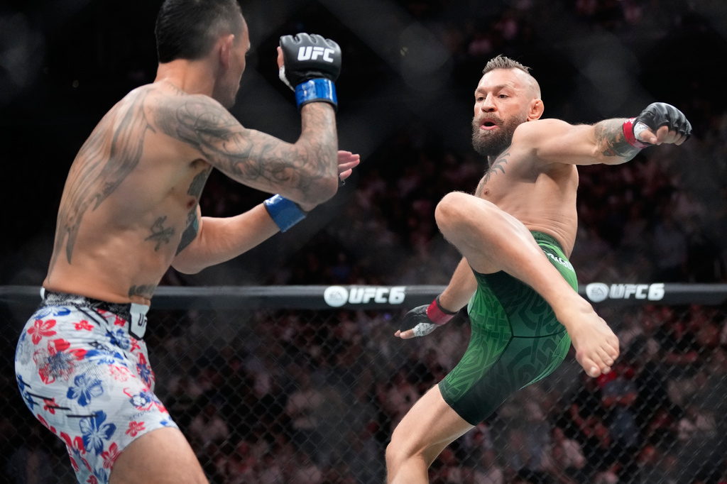 Conor McGregor, right, jumps into the air for a kick as he fights Max Holloway in a welterweight fight at the UFC 329 mixed martial arts event Saturday, July 11, 2026, in Las Vegas. (AP Photo/John Locher)