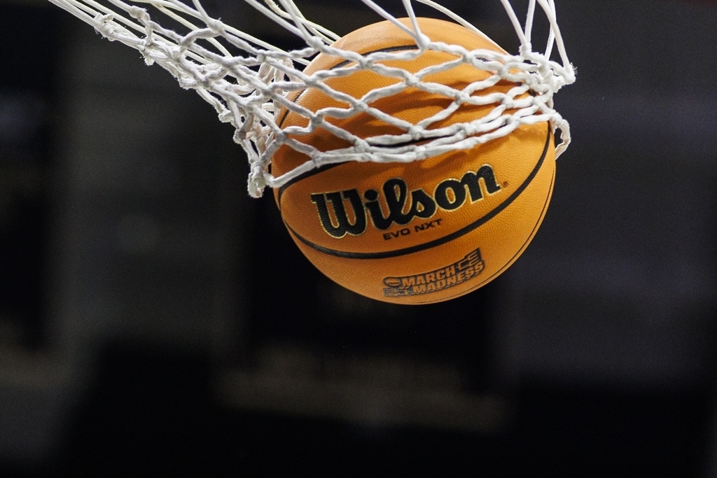 FILE - A basketball with a March Madness logo is seen going through a net prior to a second round of the NCAA college basketball tournament between Notre Dame and Michigan, March 23, 2025, in South Bend, Ind. (AP Photo/John Mersits, File)