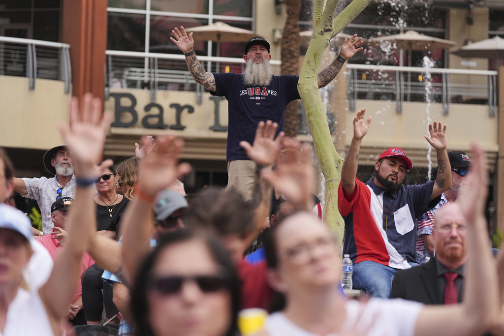 People sing along to a worship song in the overflow area outside before a memorial for conservative activist Charlie Kirk, Sunday, Sept. 21, 2025, at State Farm Stadium in Glendale, Ariz. (AP Photo/Jae C. Hong)