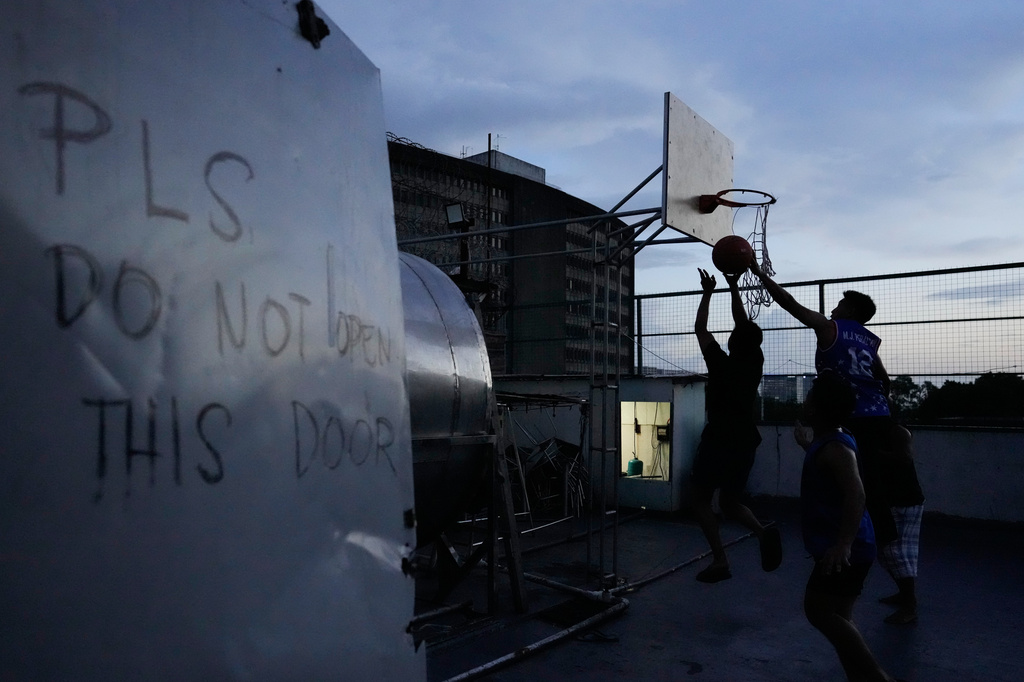 Employees play basketball as they take a break while working at the Presidential Anti-Organized Crime Commission temporary detention center, a former scam compound in Pasay, Philippines, Tuesday, June 3, 2025. (AP Photo/Aaron Favila)